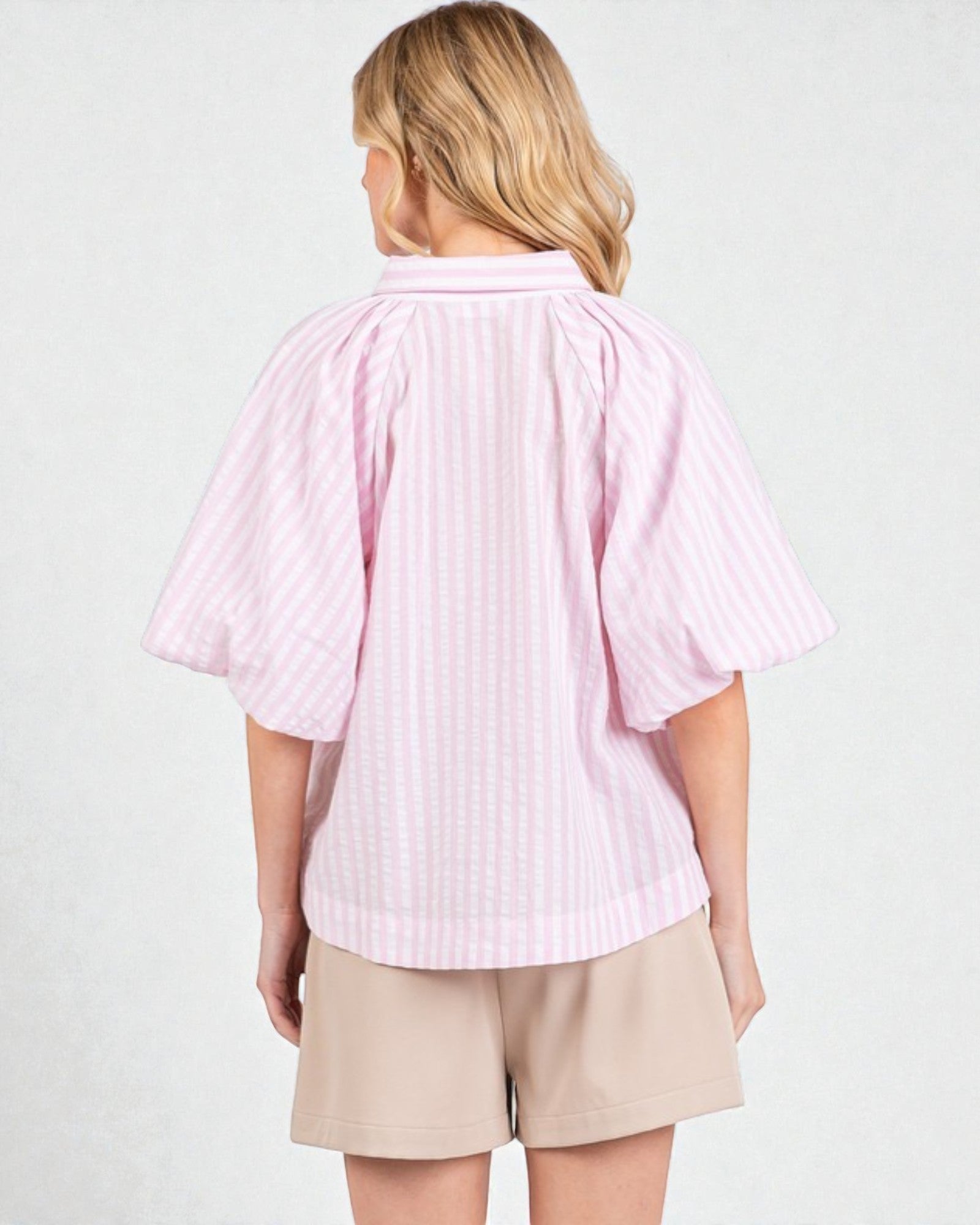 Person wearing a pink striped shirt and beige shorts on a white background