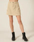 Person wearing a beige skirt and black boots on a light background