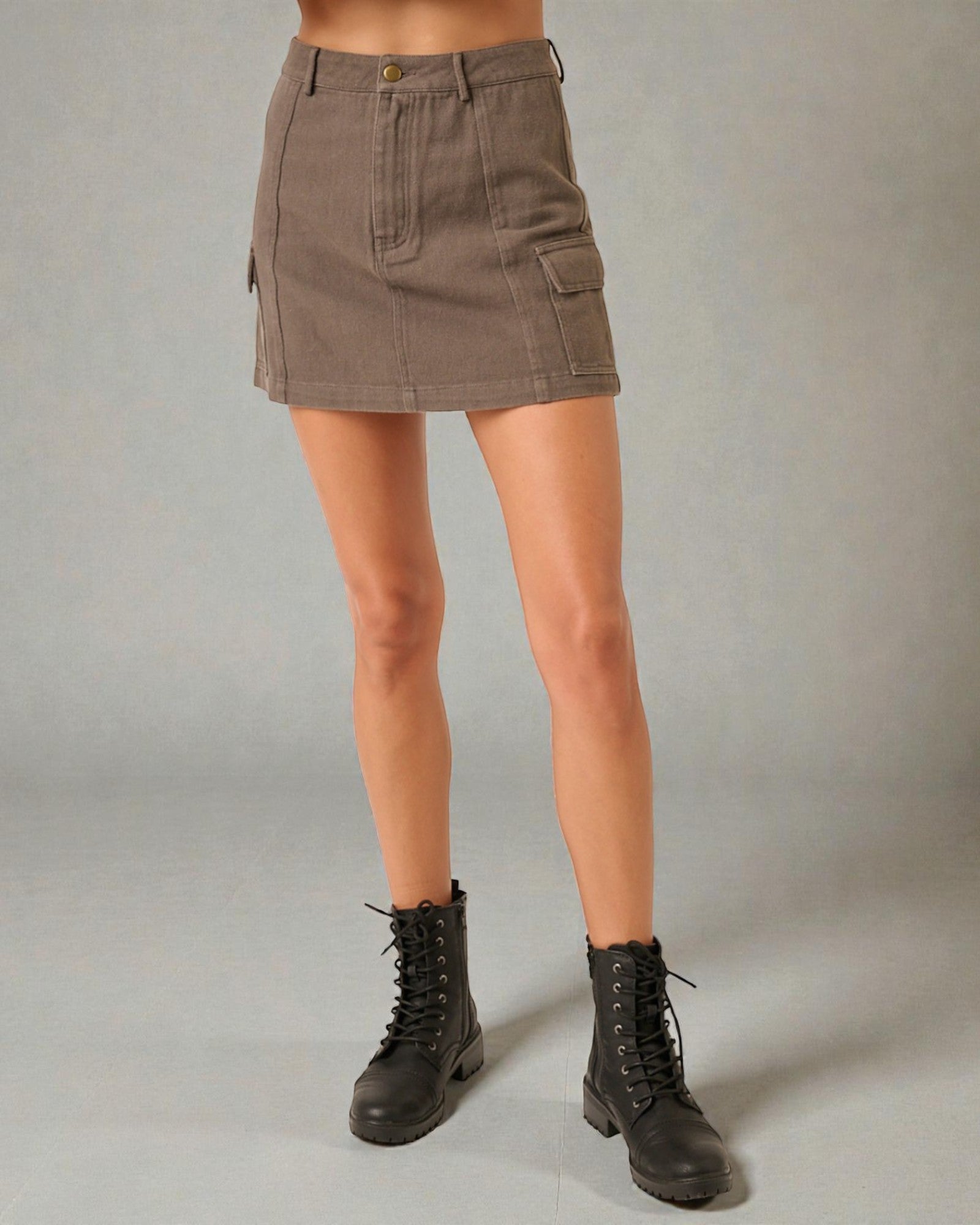 Person wearing a brown mini skirt and black boots on a gray background