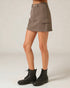 Person wearing a brown skirt and black boots on a plain background