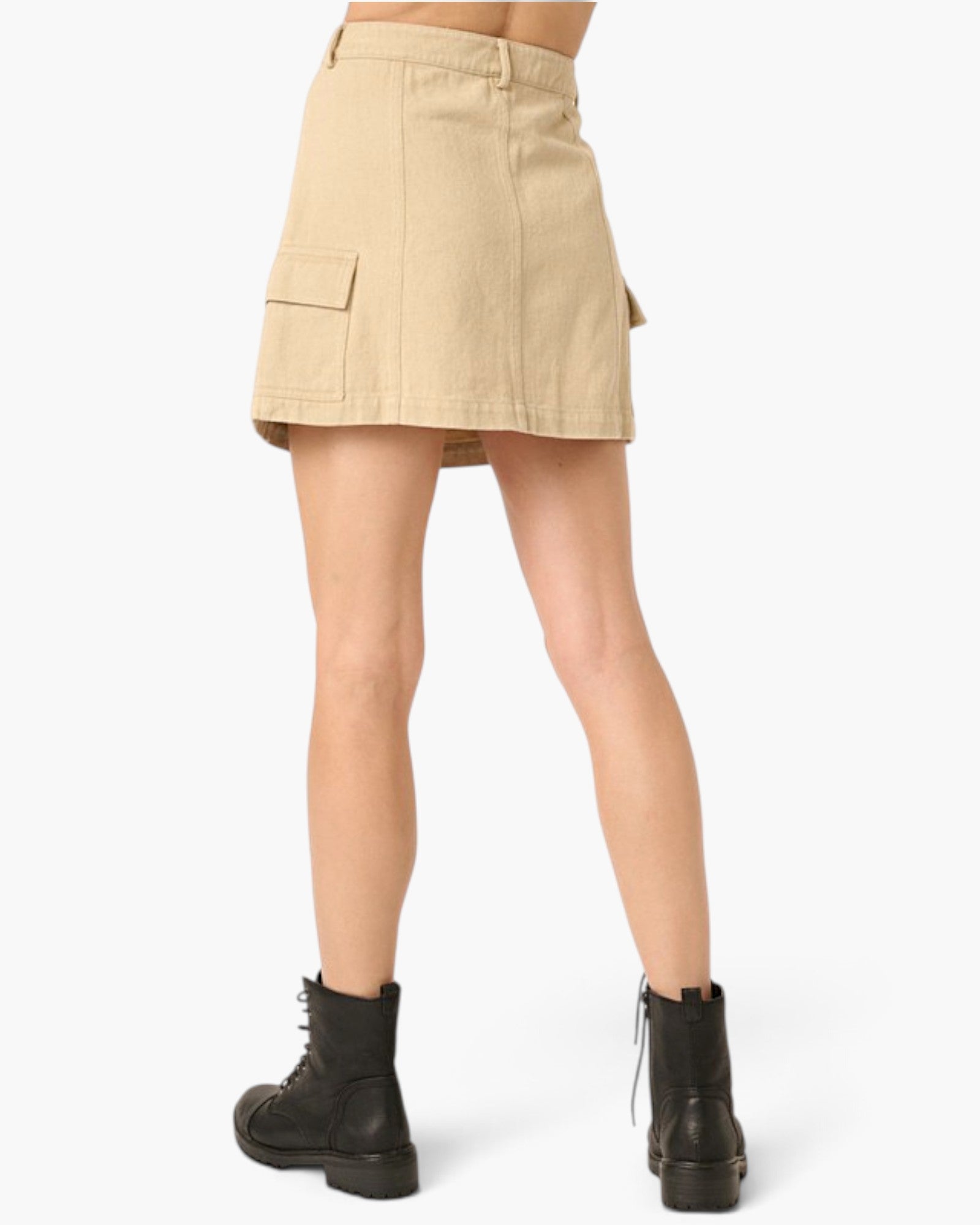 A model's lower body wearing a beige cargo-style mini skirt and black combat boots, shown from the back against a light gray studio background.