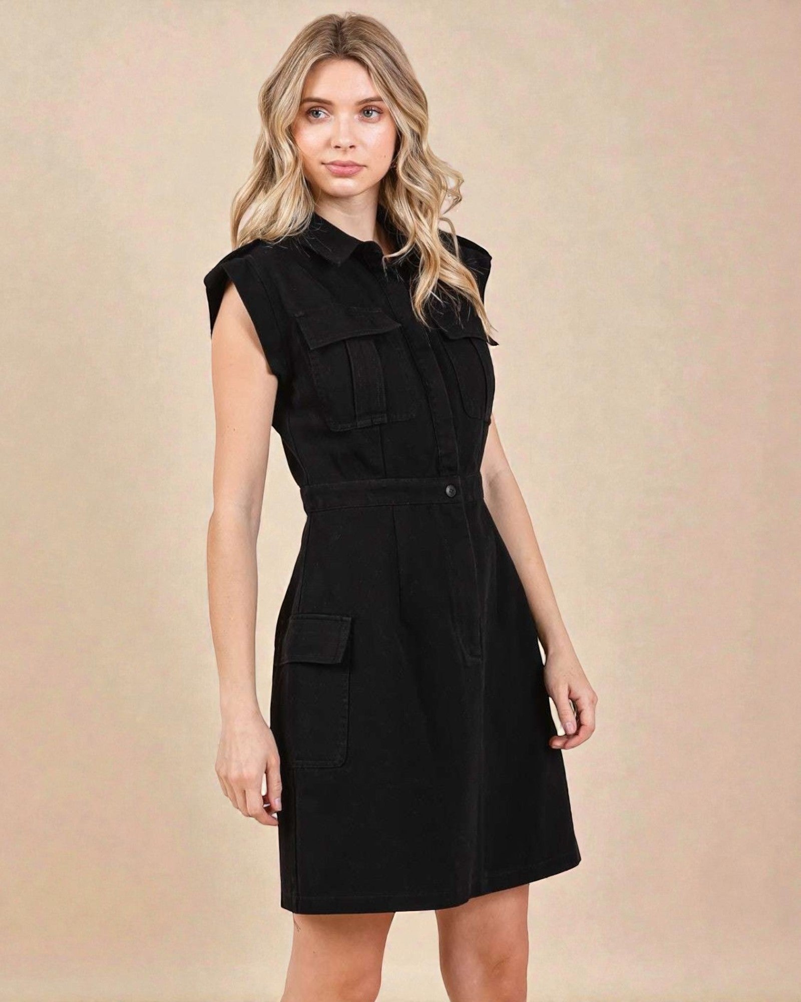 Woman wearing a black sleeveless dress with pockets on a beige background