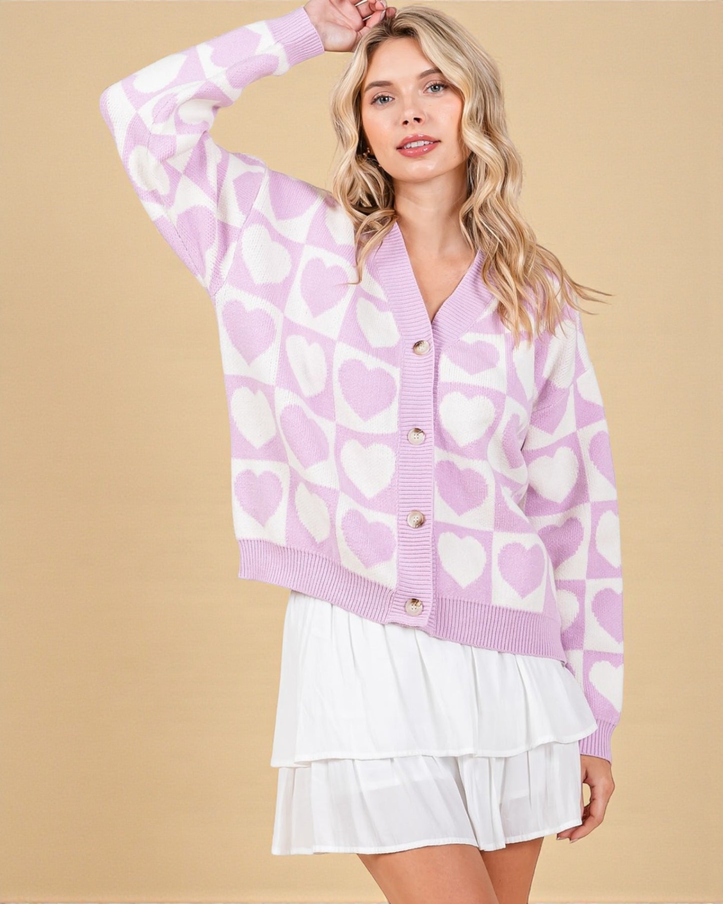 Woman wearing a purple cardigan with heart pattern against a beige background