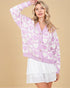 Woman wearing a purple cardigan with heart pattern against a beige background