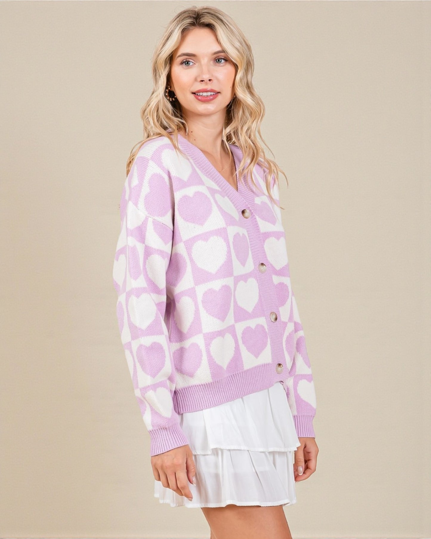 Woman wearing a purple cardigan with heart pattern on a beige background