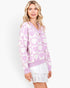 A woman wearing a lavender and white heart-patterned knit cardigan over a white ruffled mini skirt, photographed against a clean white studio background.
