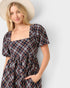 Woman wearing a plaid dress with a plain background