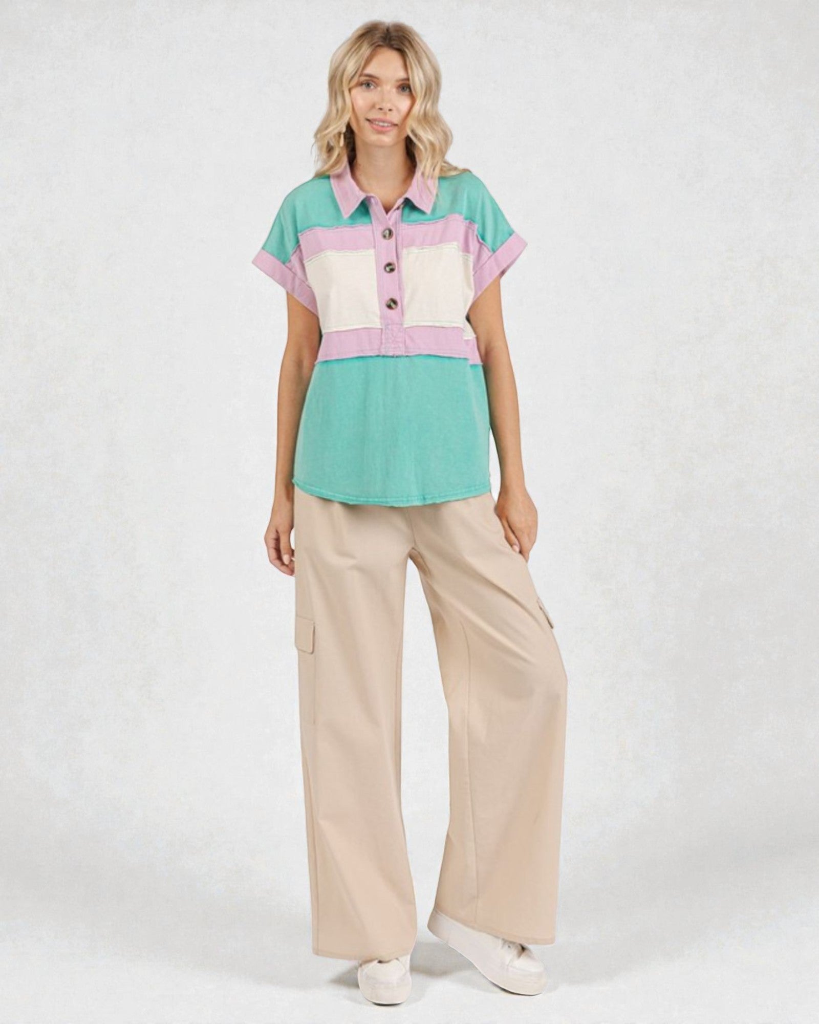Woman wearing a colorful shirt and beige pants on a white background