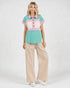 Woman wearing a colorful shirt and beige pants on a white background
