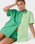 Woman wearing a green and light green button-up shirt with green shorts on a white background