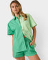 Woman wearing a green outfit with a shirt and shorts on a white background
