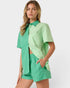 Woman wearing a green outfit with a shirt and shorts on a white background