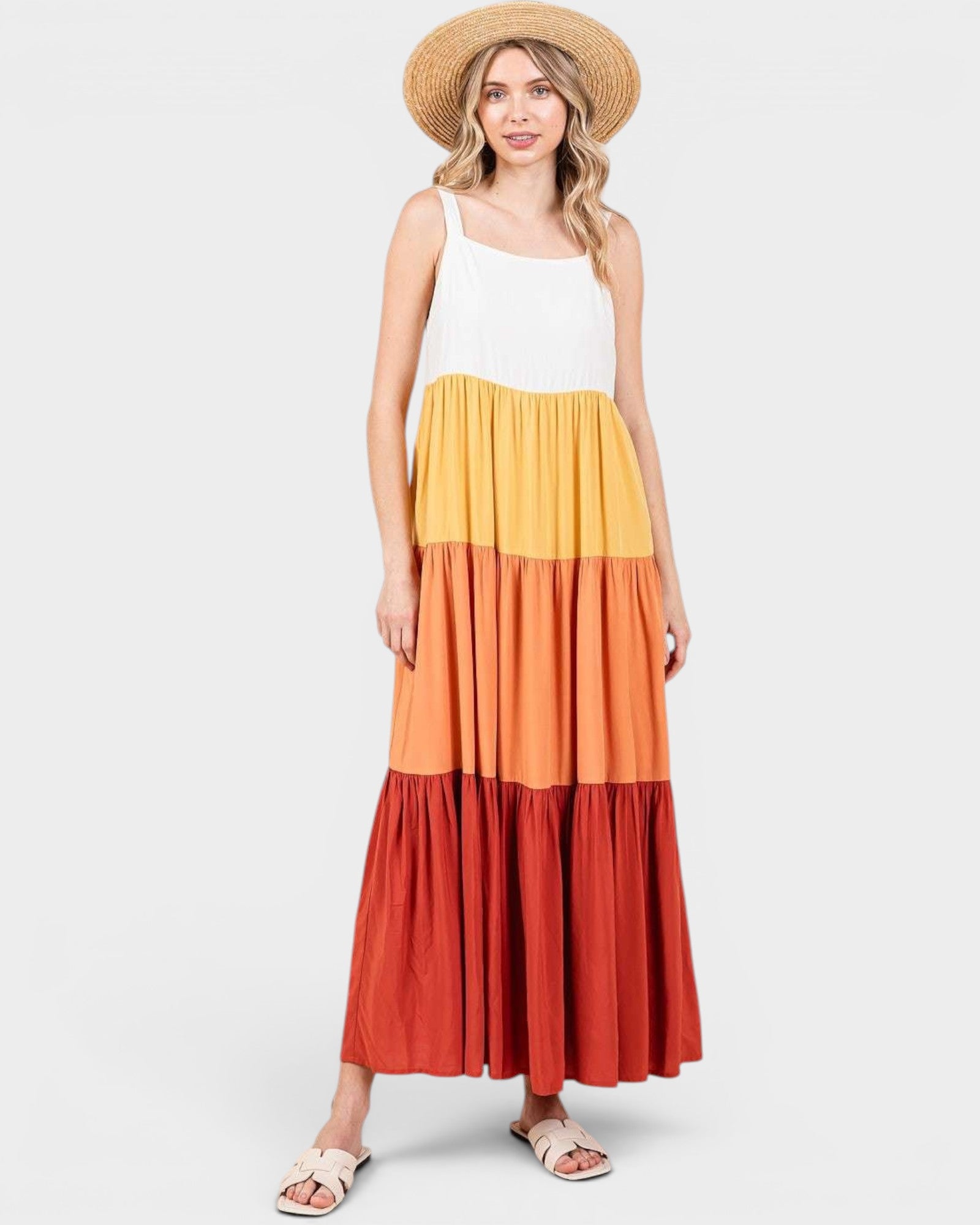 Woman wearing a multicolored dress with a white top and straw hat on a white background
