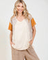 Woman wearing a beige and orange top with a plain background