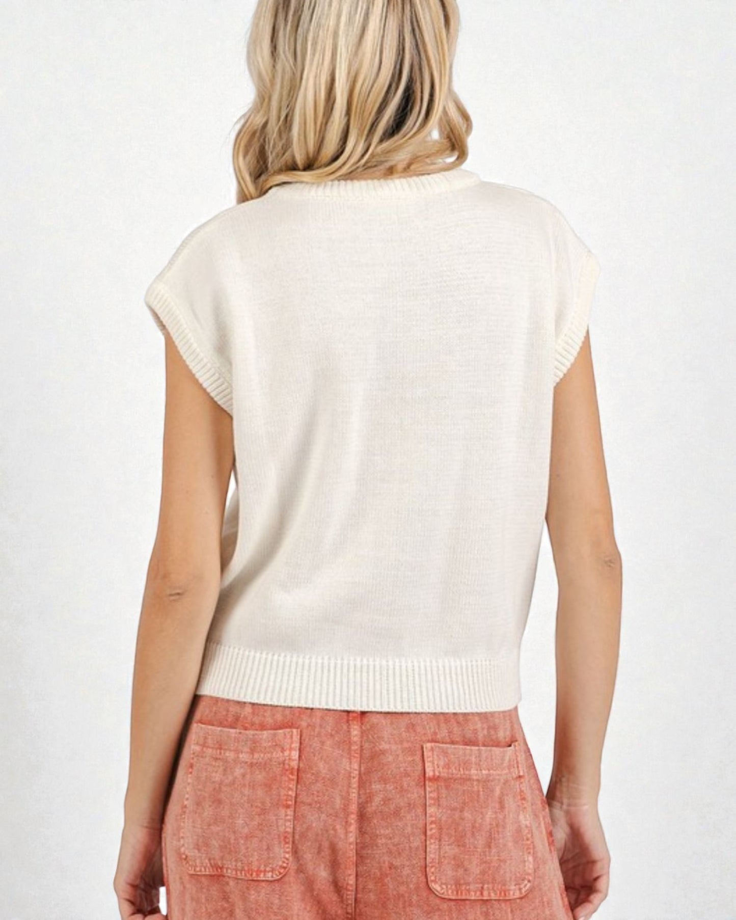 Person wearing a white sleeveless sweater over a pink skirt on a white background