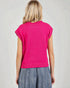 Person wearing a bright pink sleeveless sweater and blue jeans on a plain background