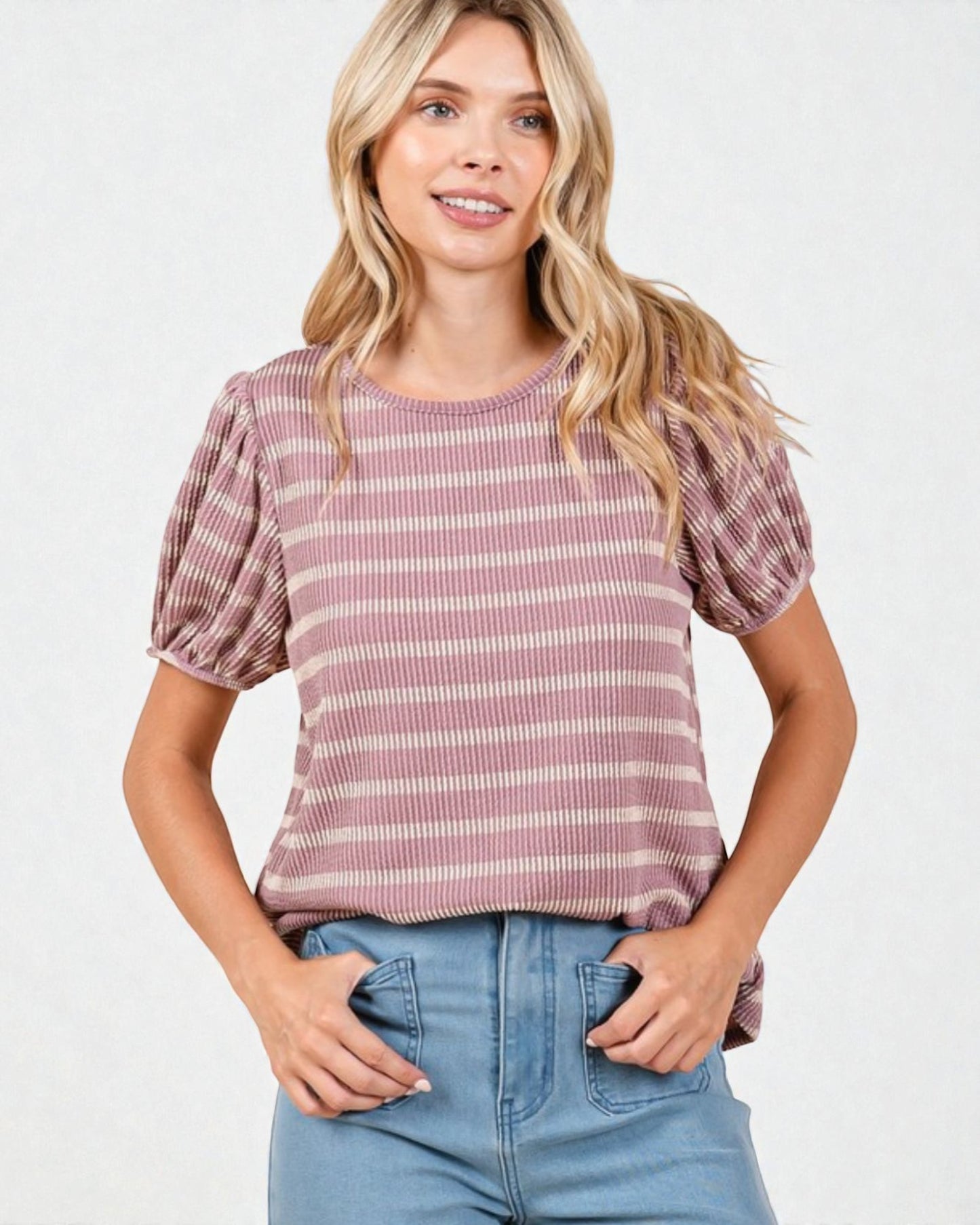 Woman wearing a striped pink and white top with puffed sleeves on a white background