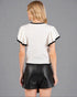 Woman wearing a white blouse with black trim and black shorts on a gray background