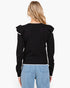 A woman viewed from the back wearing a black long-sleeve knit sweater with ruffled shoulder details and light blue jeans against a plain white background.