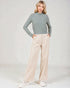 Woman wearing a green turtleneck and beige pants on a white background