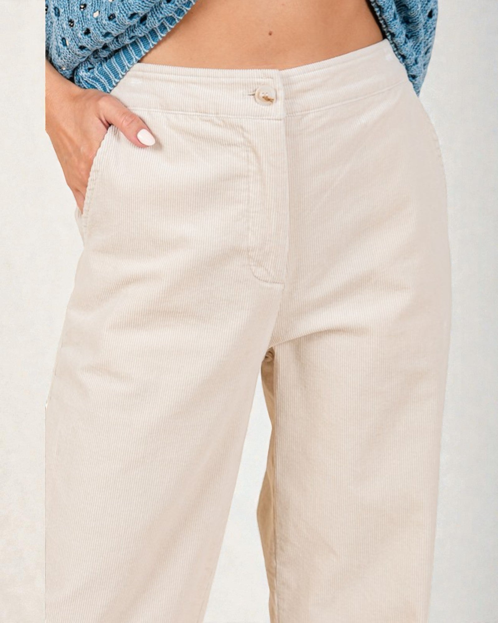 Beige pants worn by a person with a blue patterned top on a white background