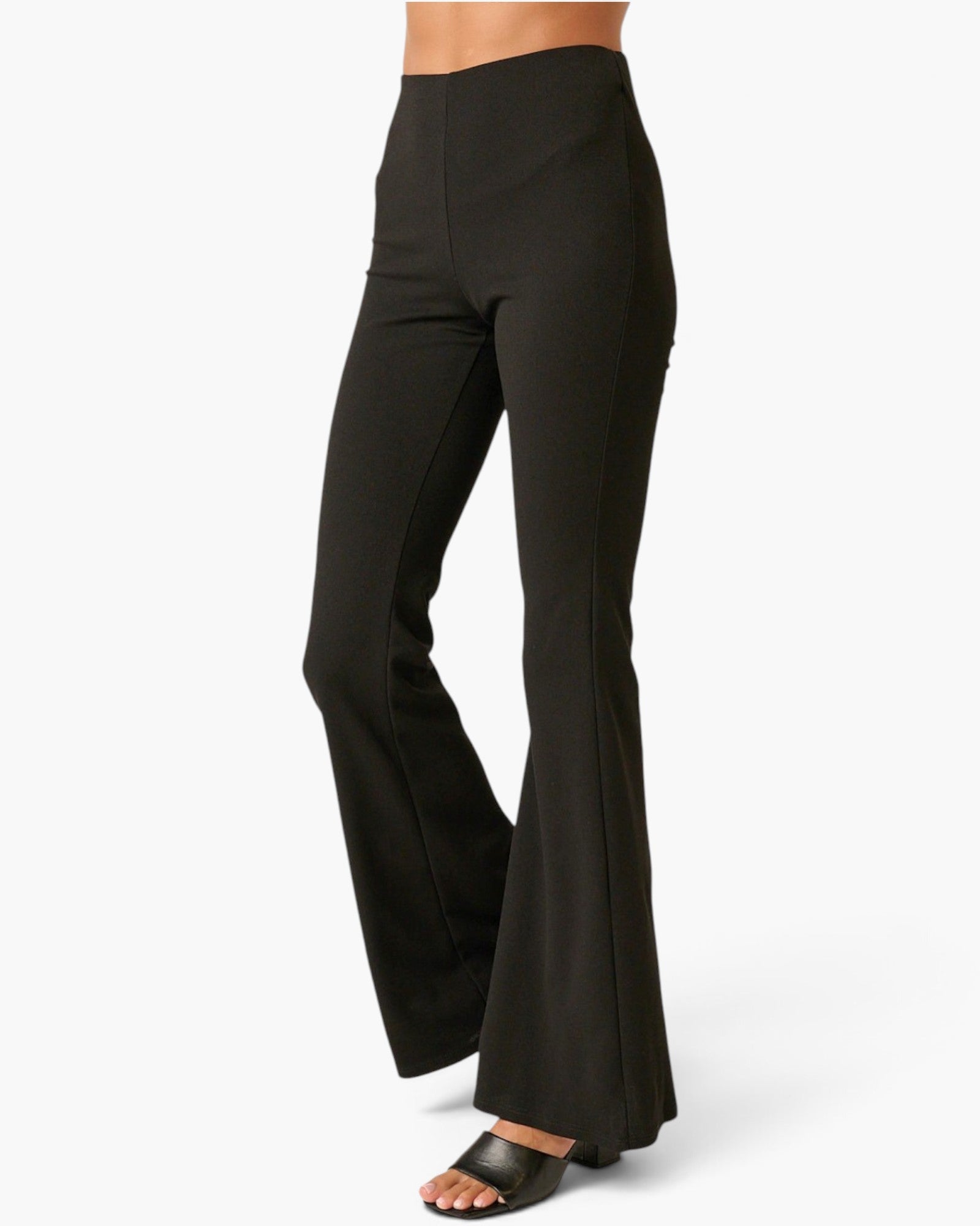 Black high-waisted flared pants shown on a model from the waist down, paired with black slide sandals against a clean white background.