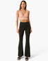 A model wearing a light pink lace crop top and black high-waisted flared pants, standing against a light gray studio background.