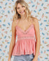 Woman wearing a pink lace-trimmed top against a colorful patterned background