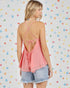 Woman wearing a pink open-back top and denim shorts against a colorful heart-patterned background
