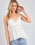 Woman wearing a white lace-trimmed top against a plain background