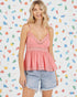 Woman wearing a pink lace top and denim shorts against a colorful patterned background