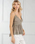 Woman wearing a beige lace-trimmed top against a white wall