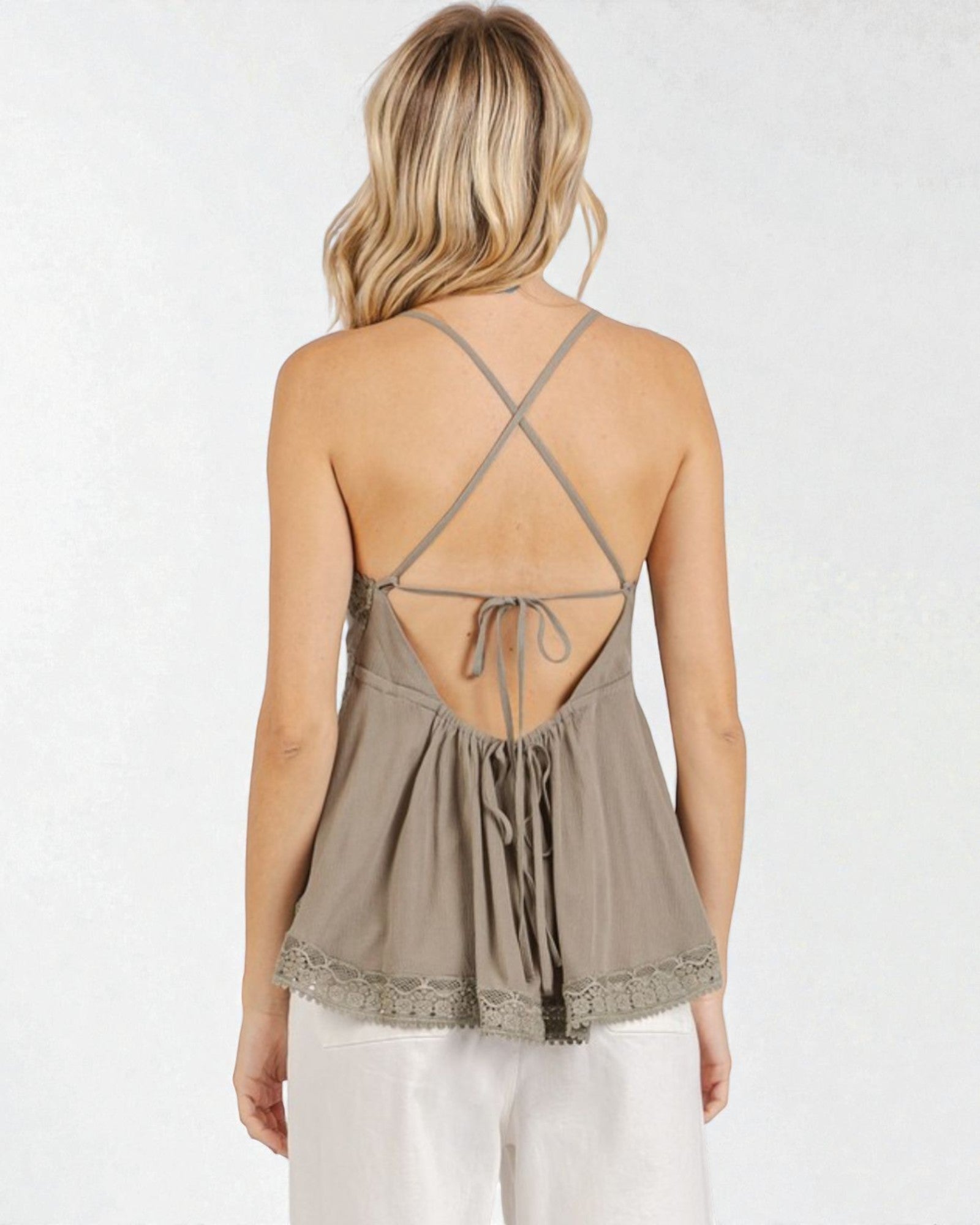 Woman wearing a beige strappy top with lace details on a white background