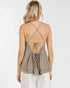 Woman wearing a beige strappy top with lace details on a white background