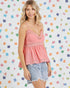 Woman wearing a pink top and denim shorts against a colorful geometric patterned background