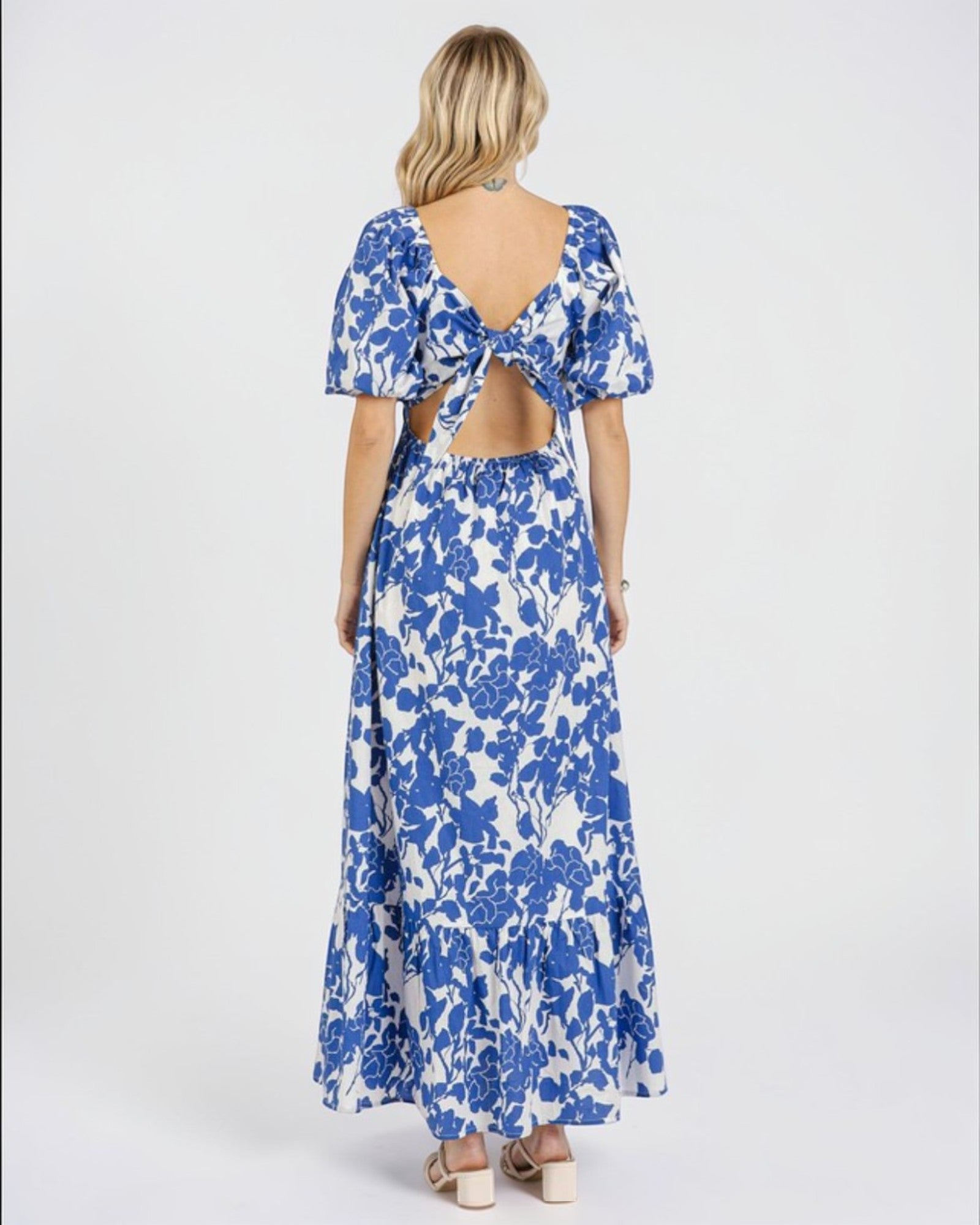 Woman wearing a blue floral dress with an open back on a white background