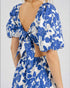 Blue and white floral dress with open back and puff sleeves on a plain background