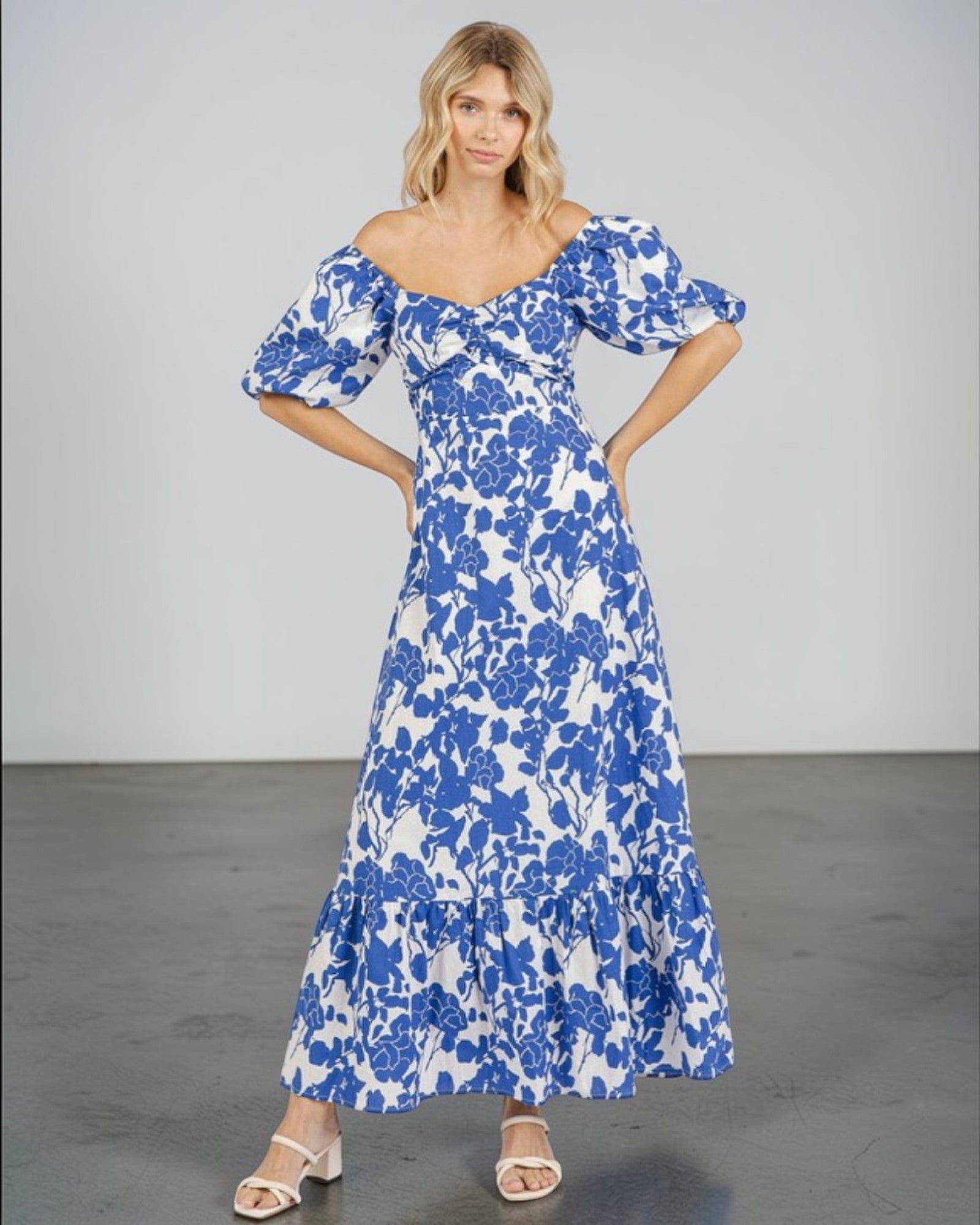 Woman wearing a blue floral off-shoulder dress against a plain background