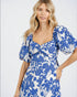 Woman wearing a blue and white floral dress on a plain background