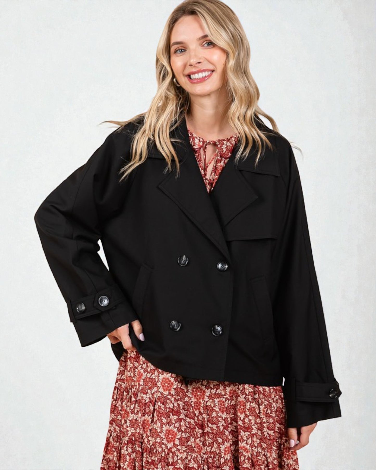 Woman wearing a black jacket over a floral dress on a white background