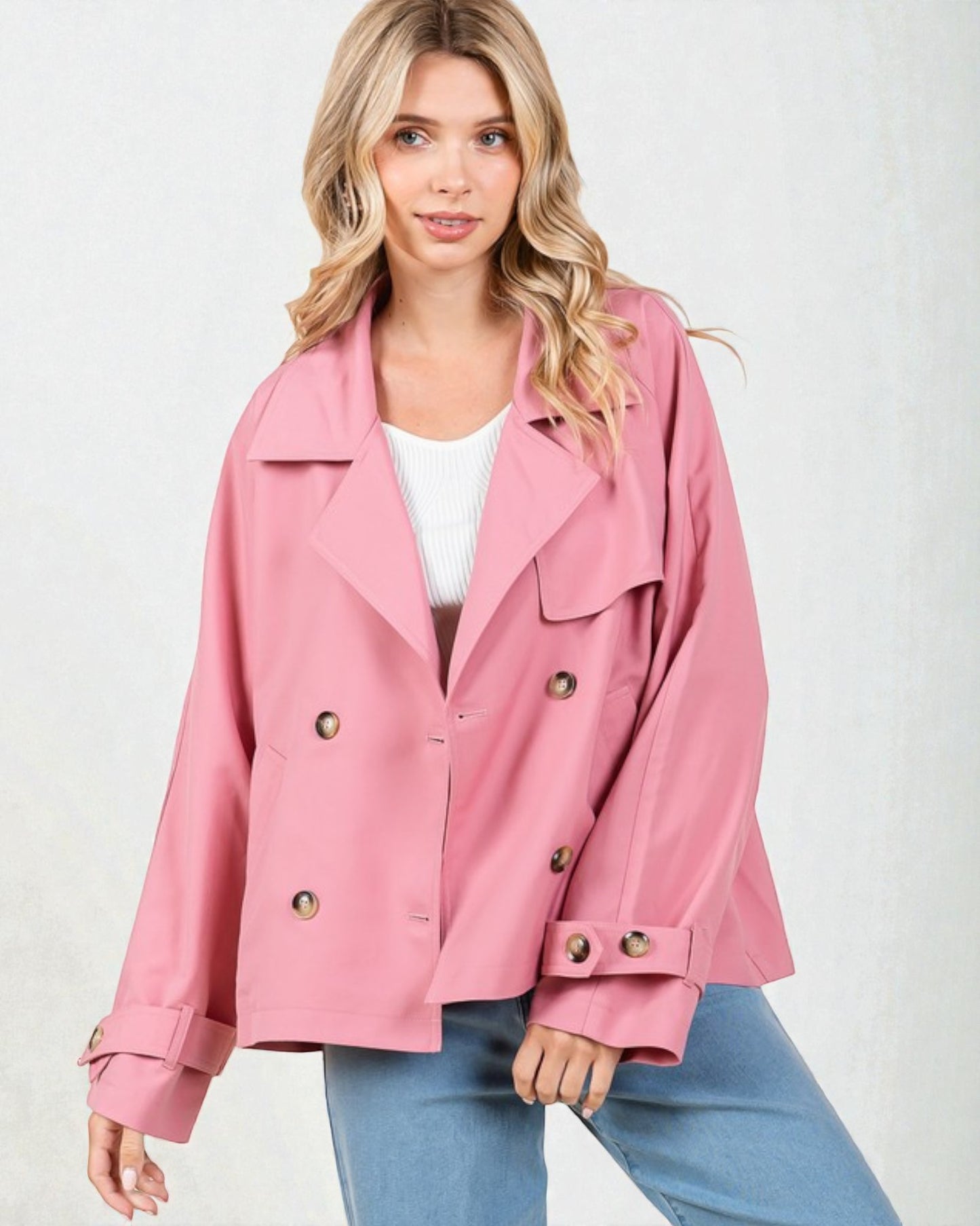 Woman wearing a pink jacket with gold buttons on a white background