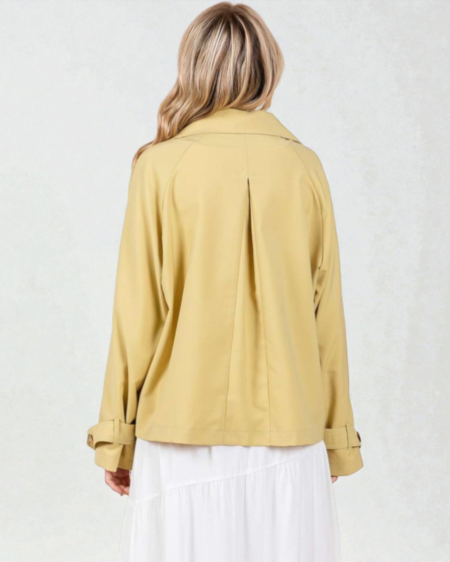 Person wearing a mustard yellow jacket on a white background