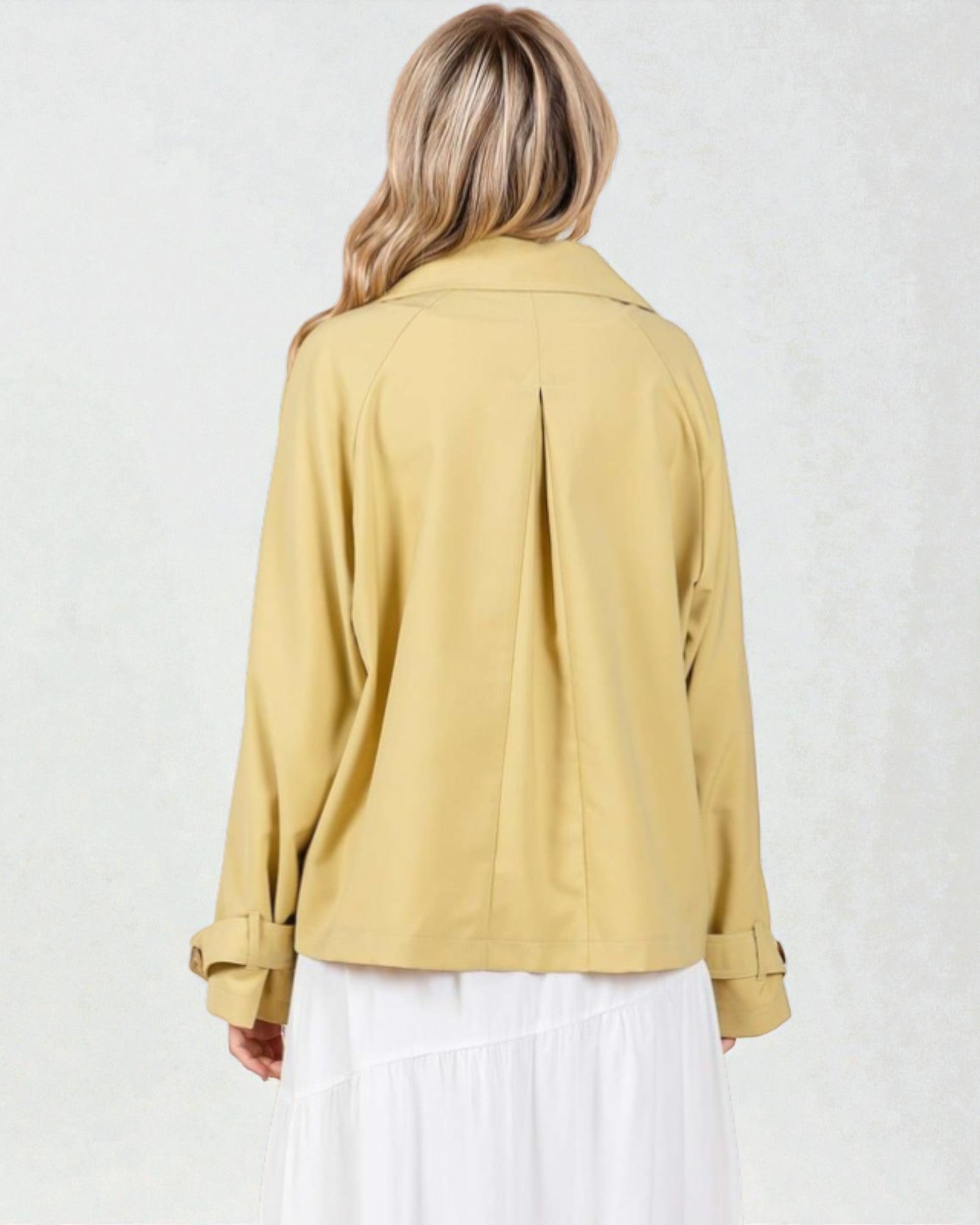Person wearing a mustard yellow jacket on a white background