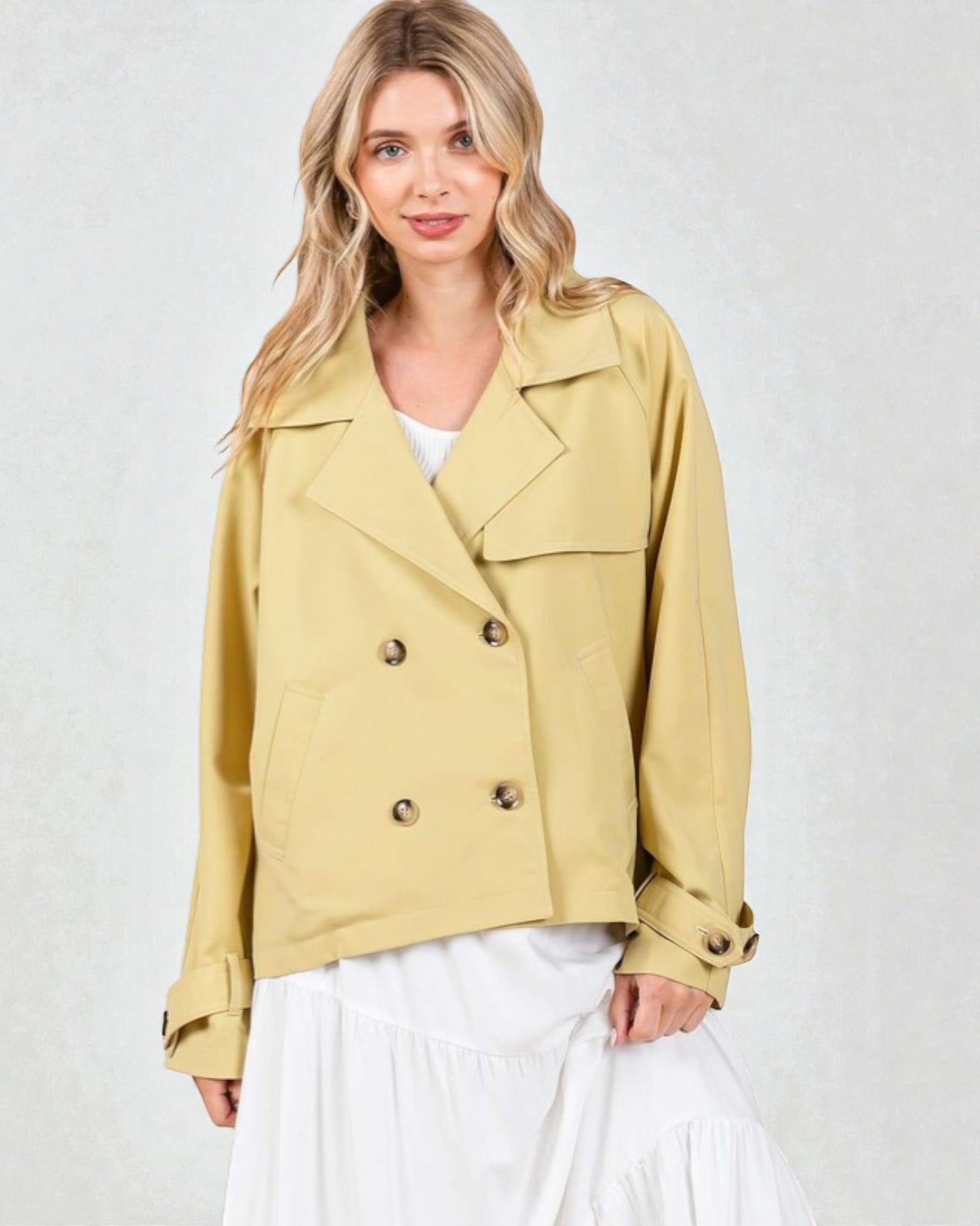 Woman wearing a beige jacket with button details on a white background