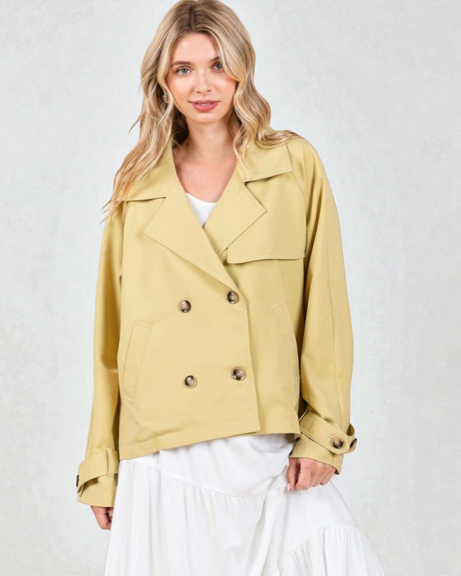 Woman wearing a beige jacket with button details on a white background