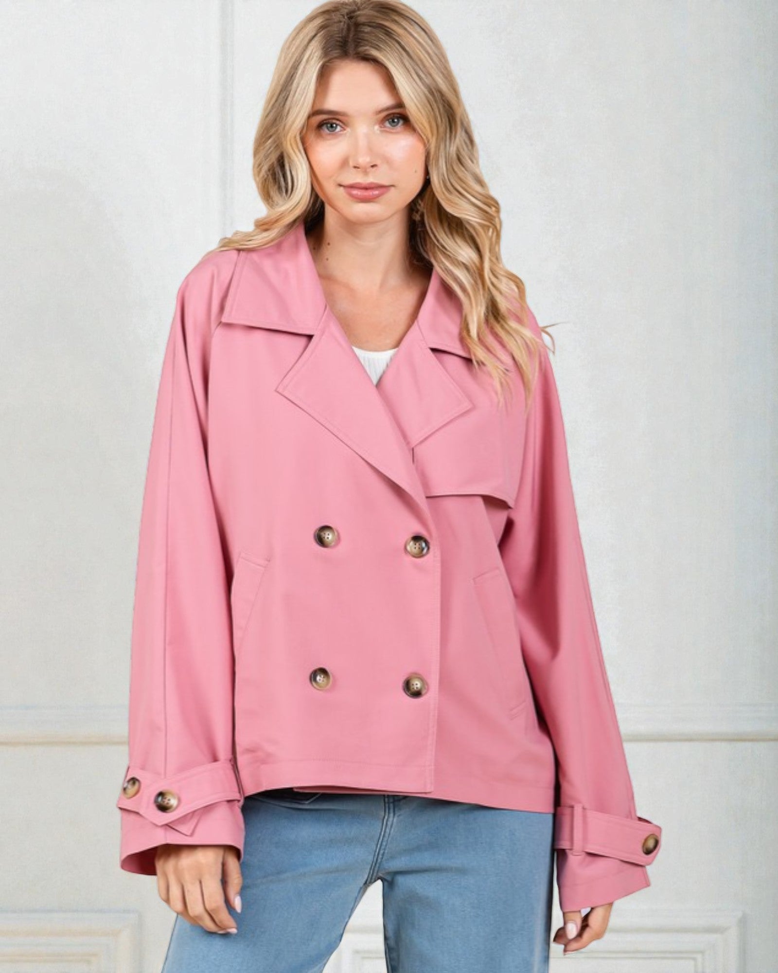 Woman wearing a pink jacket with gold buttons against a white background