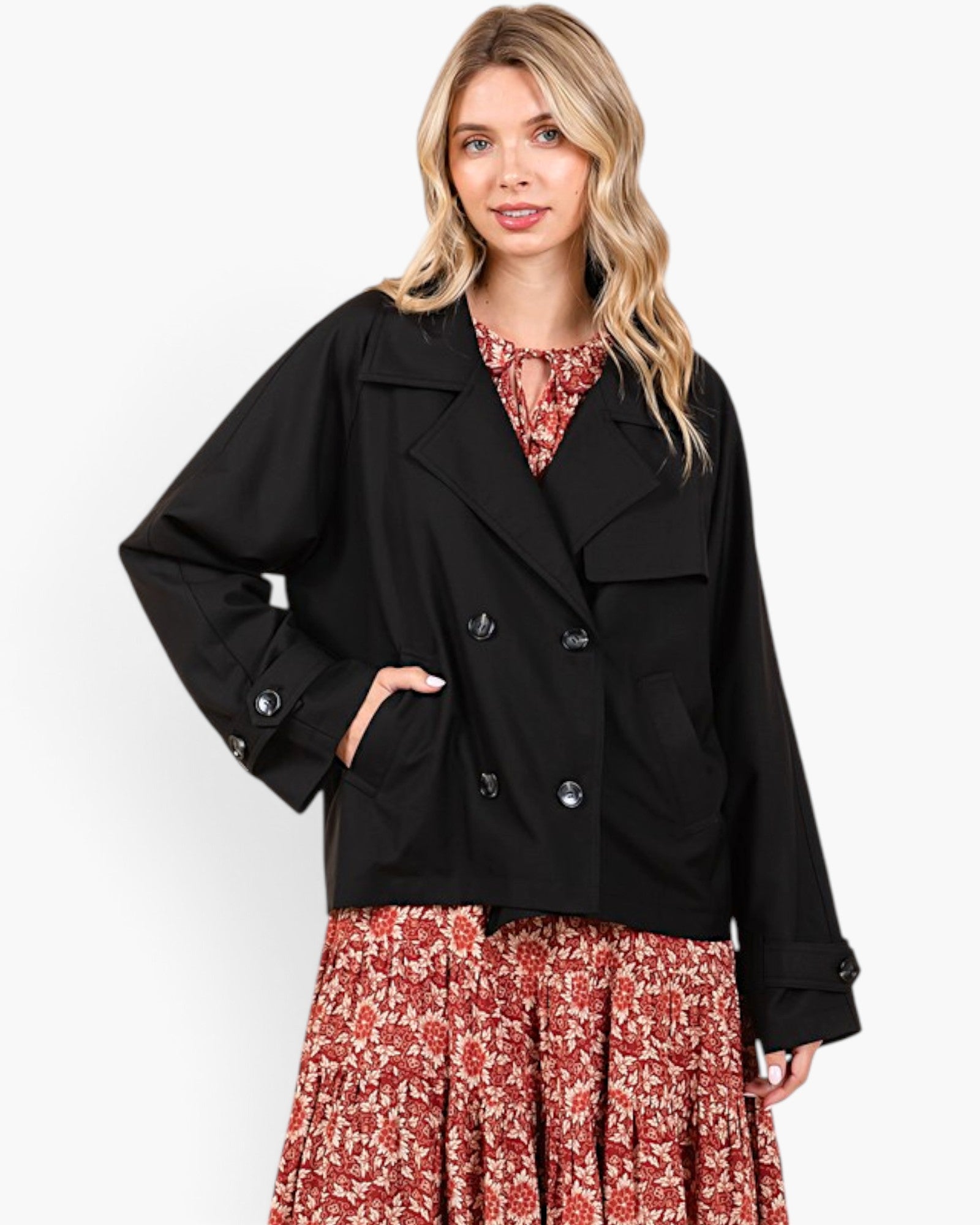 A woman modeling a black double-breasted blazer over a red and white floral print top and matching skirt, set against a plain white studio background.