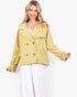 A woman modeling a cropped, double-breasted blazer in a light mustard yellow color, styled with a white top and white tiered maxi skirt against a plain white studio background.