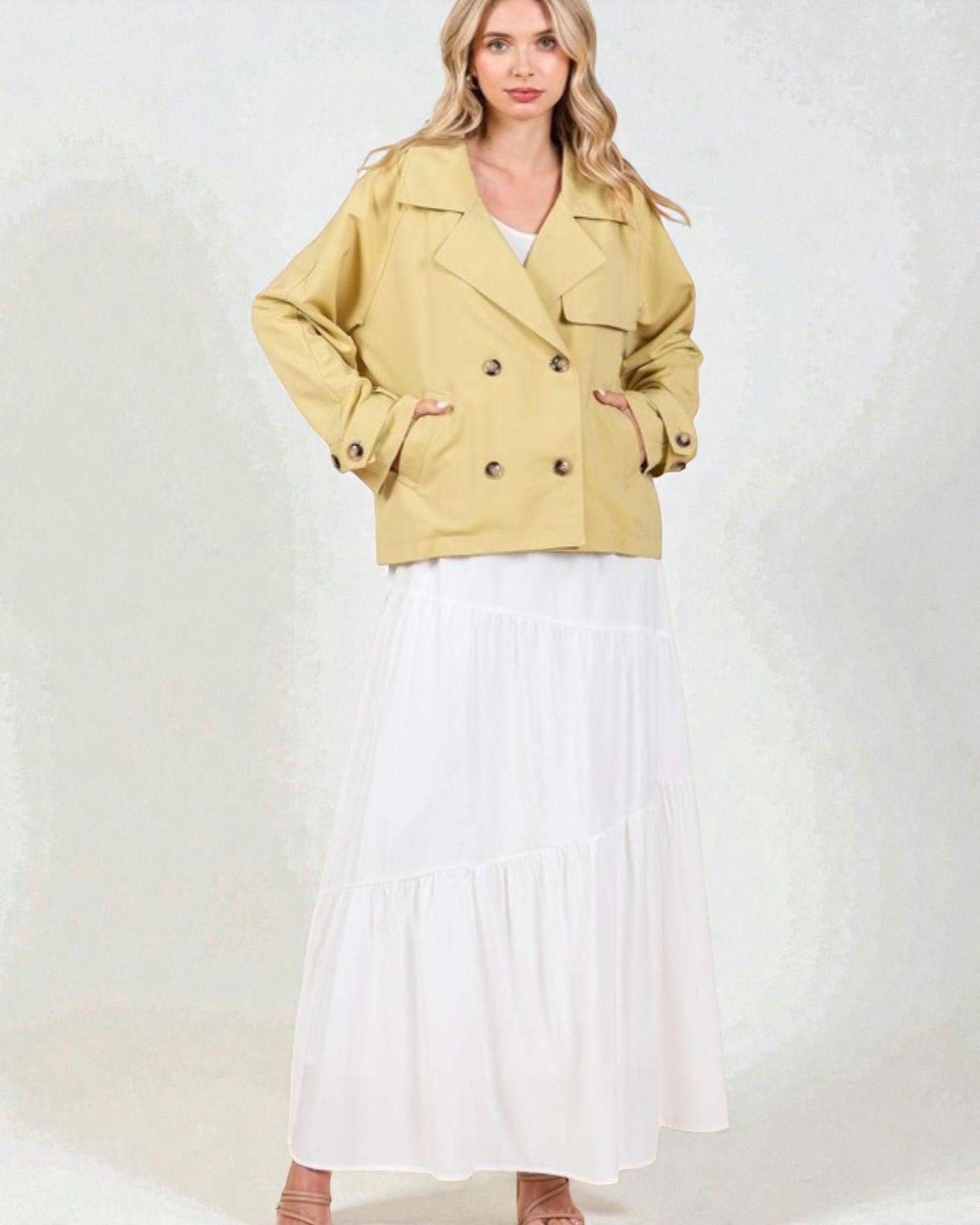 Woman wearing a beige jacket over a white dress on a white background