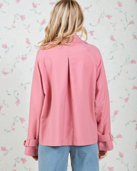 Person wearing a pink jacket with floral wallpaper background